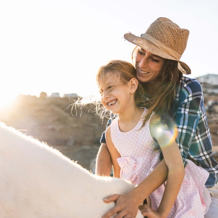 A woman and a young girl riding a horse together